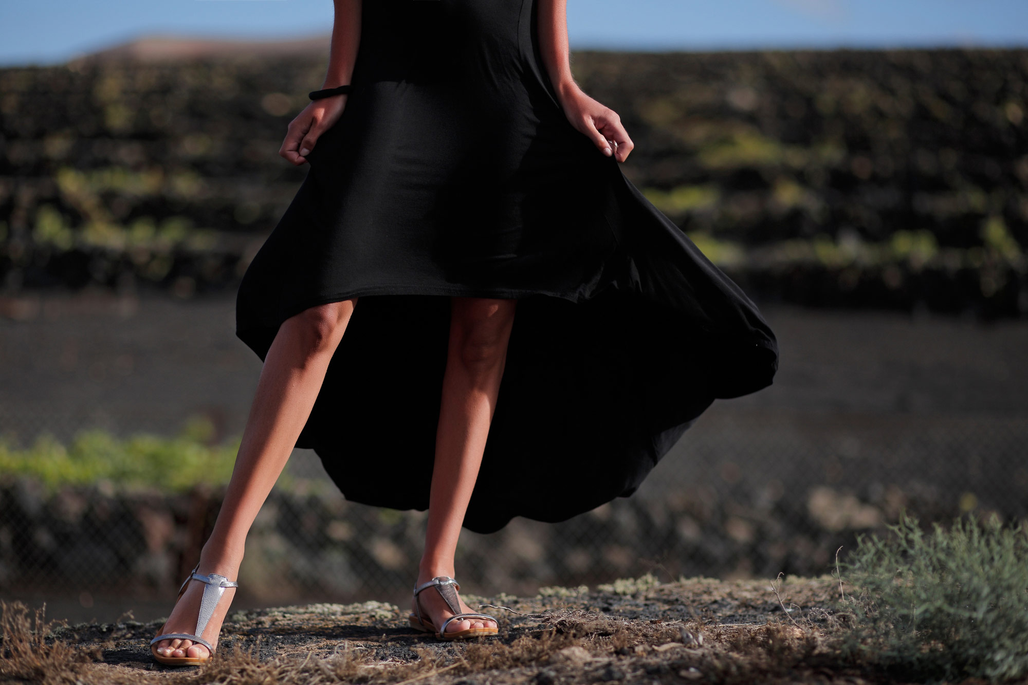 vulcano sullo sfondo di una vigna a Lanzarote modella indossa sandali argento