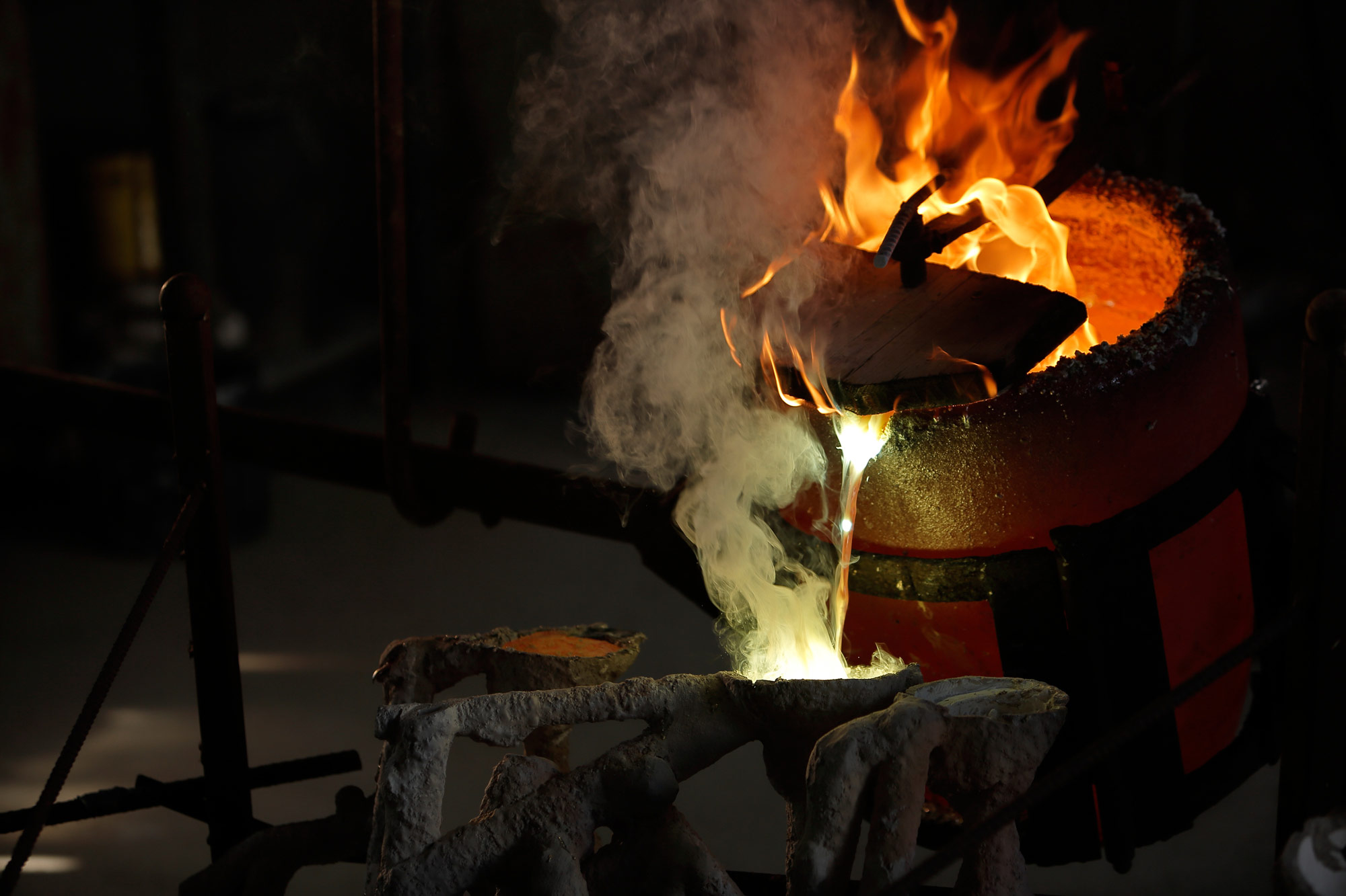 bronzo fusione dal crogiolo cola il bronzo fuso nello stampo e il fumo e le fiamme si alzano