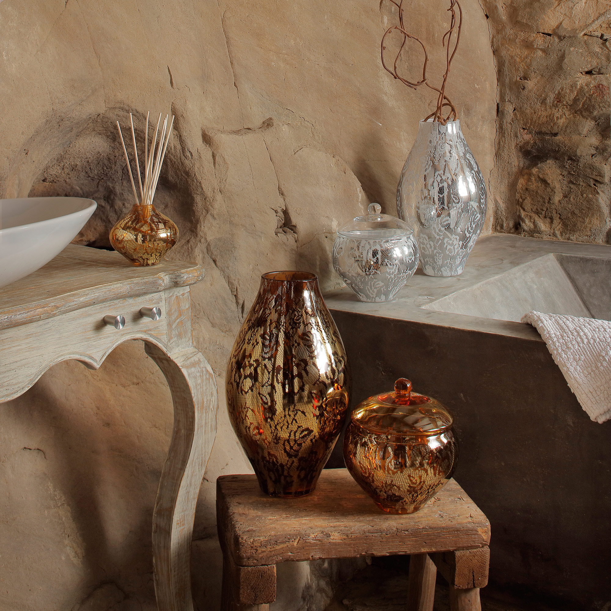 vasi di cristallo con oro e argento ambientati in un bagno di pietra