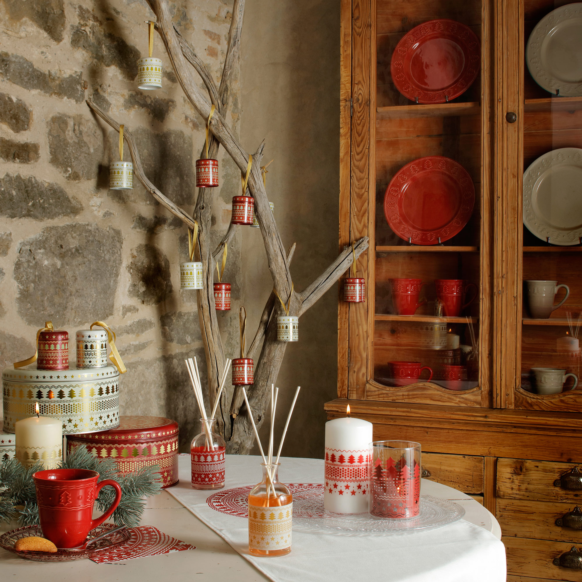 porta fragranze con decoro natalizia ambientati su un tavolo con una madia piena di piatti e tazze in ceramica